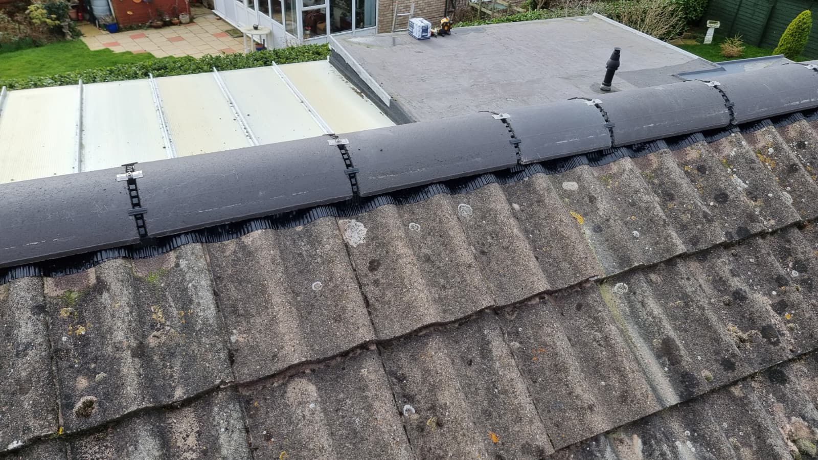 Ridge tile dry-fix system being fitted on a pitched roof