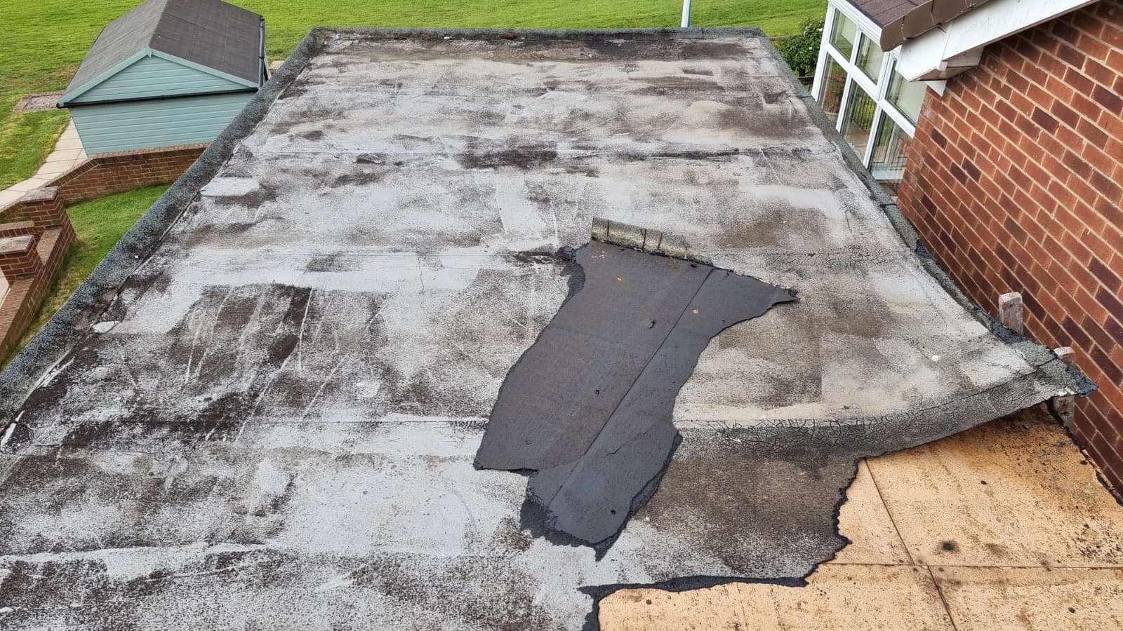 Damaged flat roof with torn felt needing urgent repair