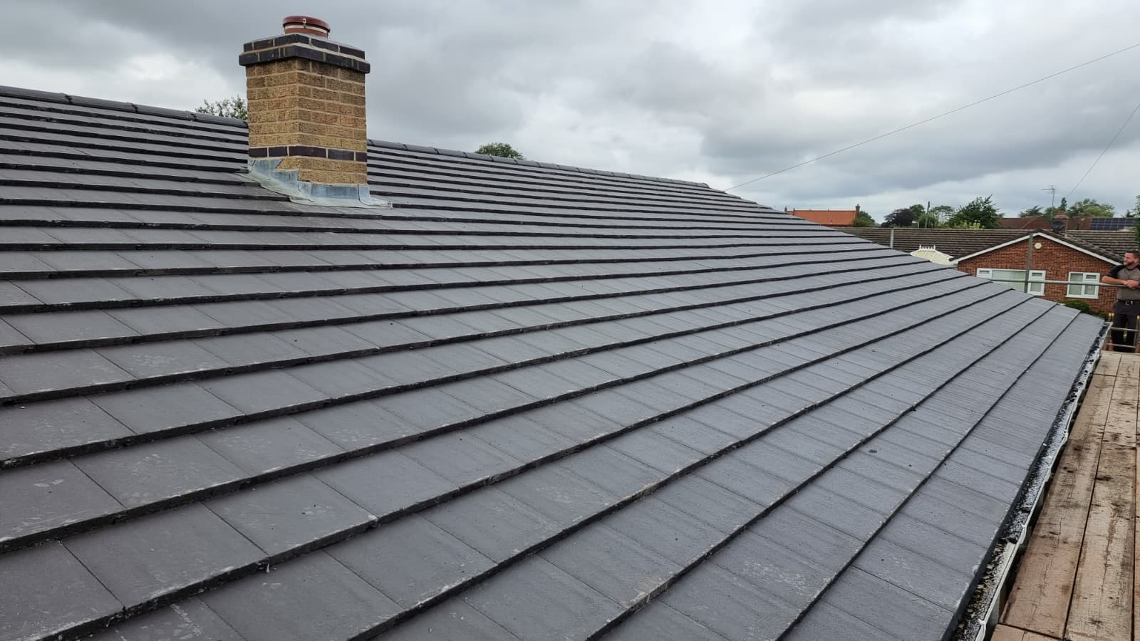 Completed grey tiled roof with re-pointed brick chimney on bungalow