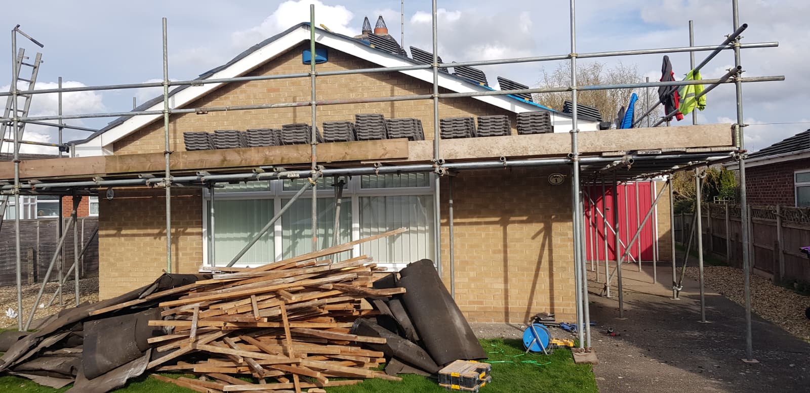 Scaffolded bungalow mid re-roof with tiles loaded out and old materials removed