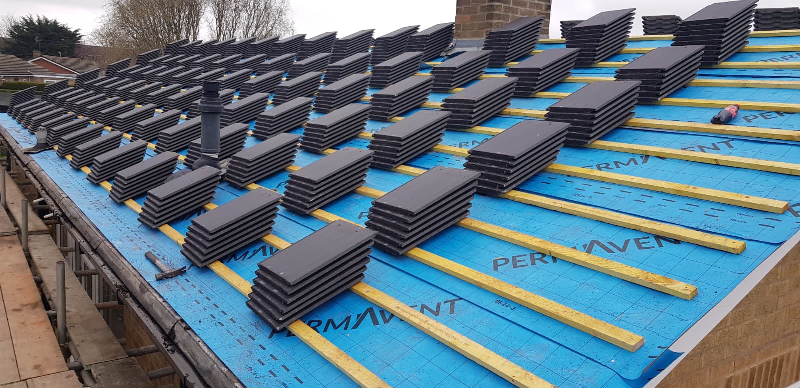 New roof tiles set out in stacks across battens on Permavent underlay