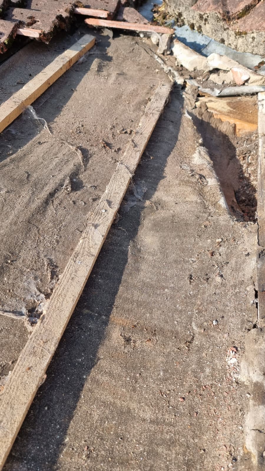 Stripped roof deck showing old perished felt and exposed battens before replacement