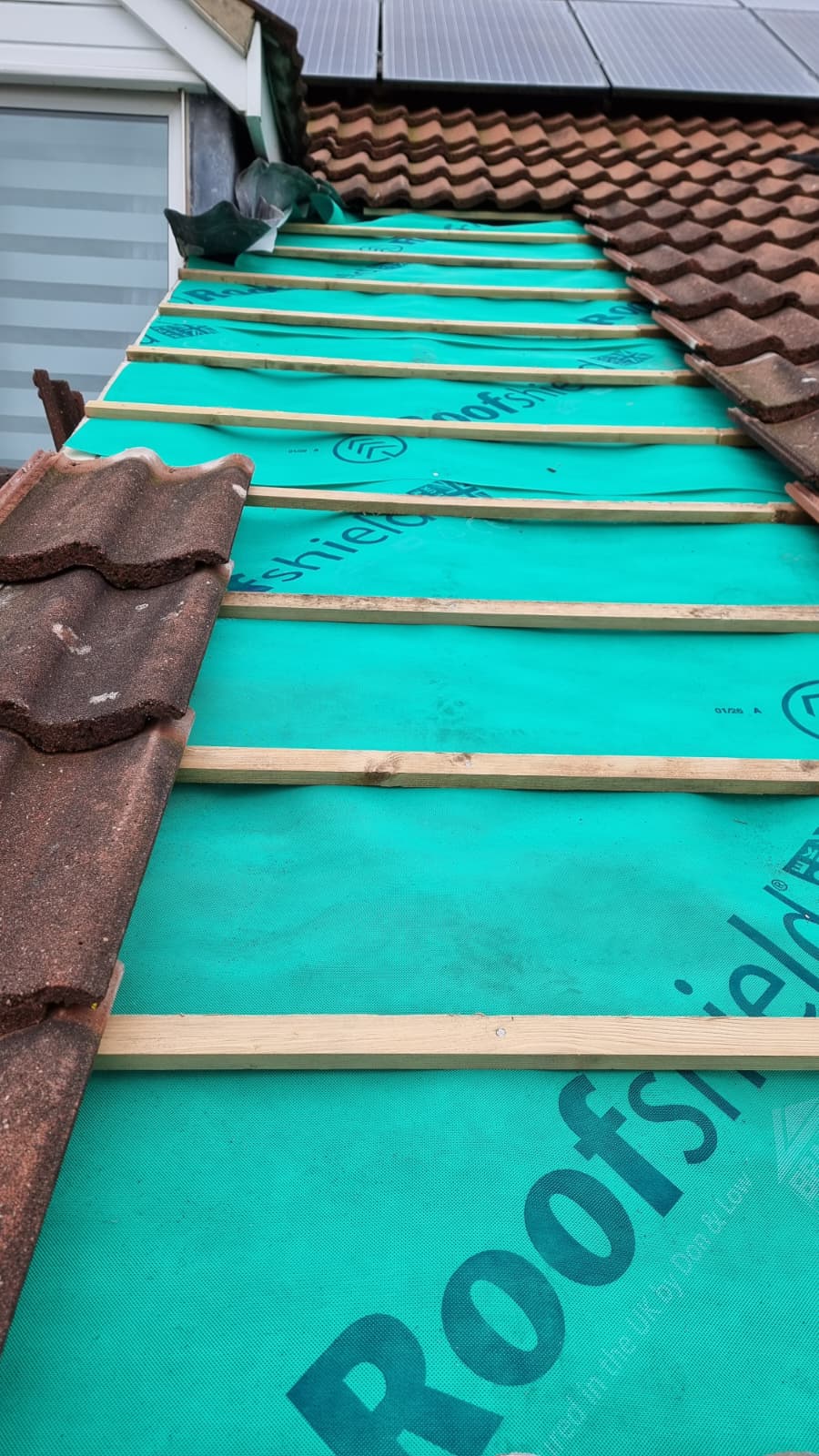 New Roofshield membrane and battens with brown tiles stacked ready to lay