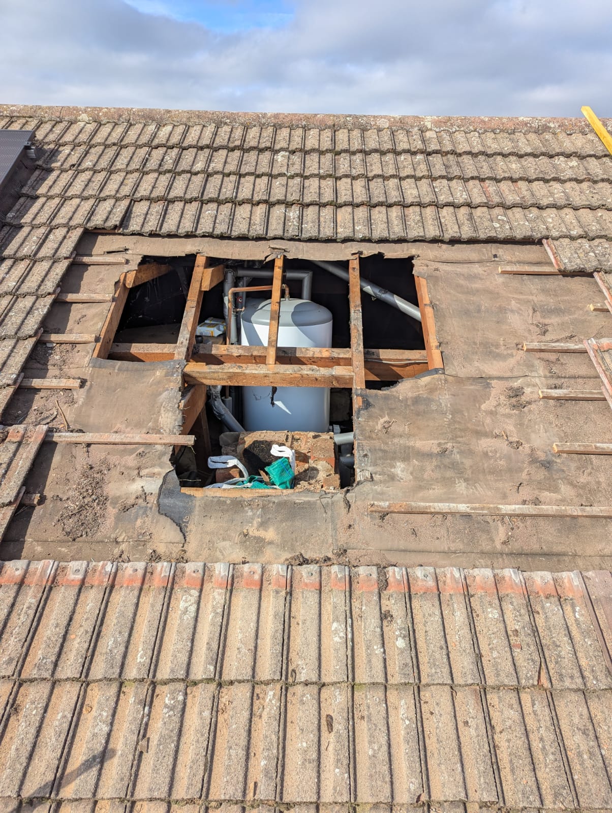Roof opened up exposing hot water cylinder in loft during full re-roof