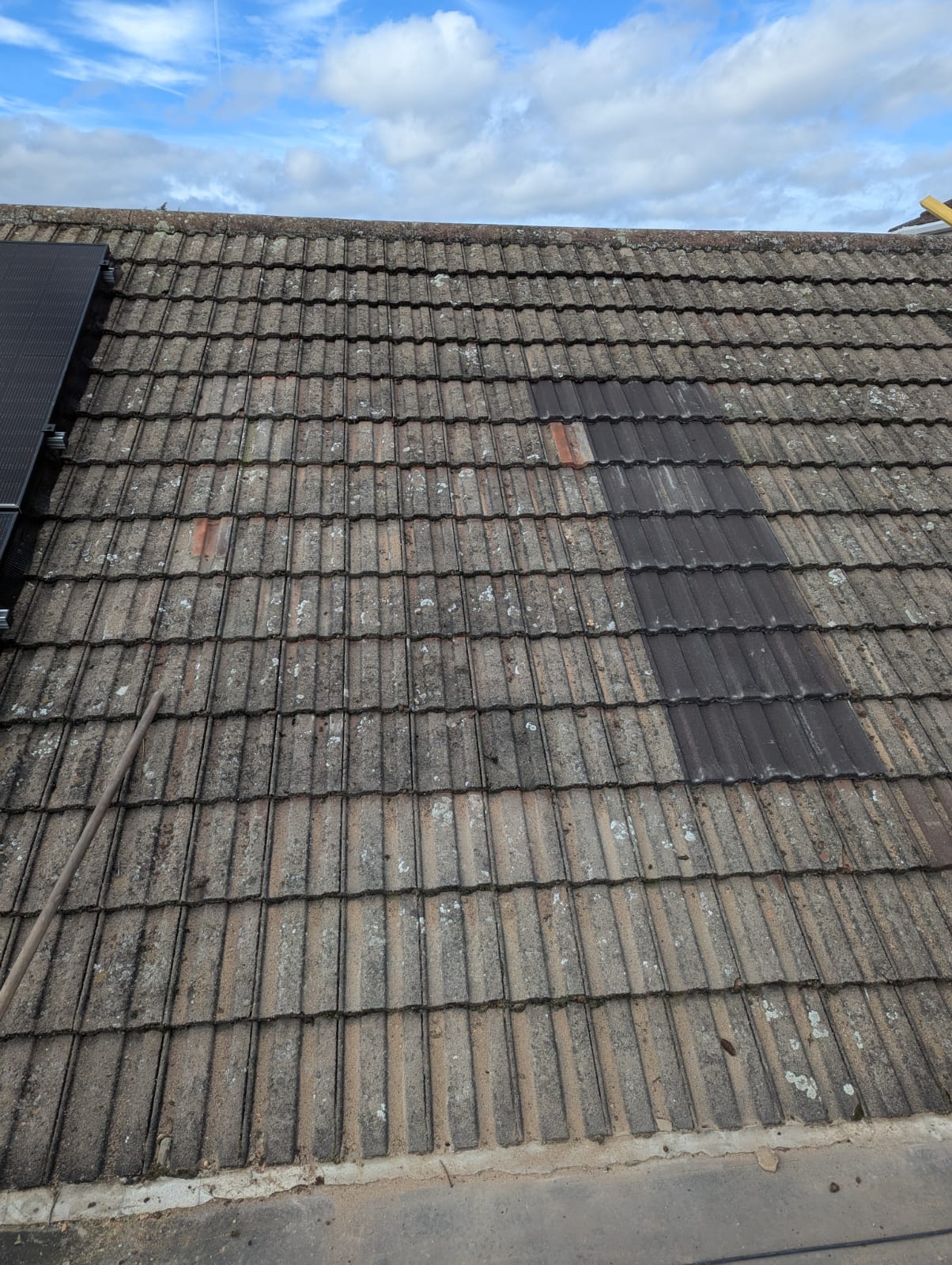 Aged concrete tile roof with moss and mismatched replacement tiles before re-roof